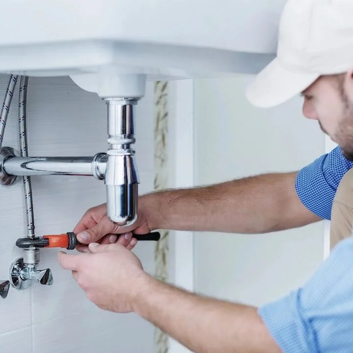 Licensed plumber repairing sink pipes for local plumbing contractor service