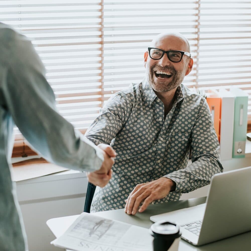 Trades business owner shaking hands with marketing partner at office desk